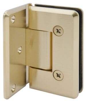 Close-up of a gold-colored glass door hinge with screws.